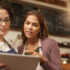 two women at small business with tablet by register