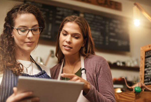 two women at small business with tablet by register